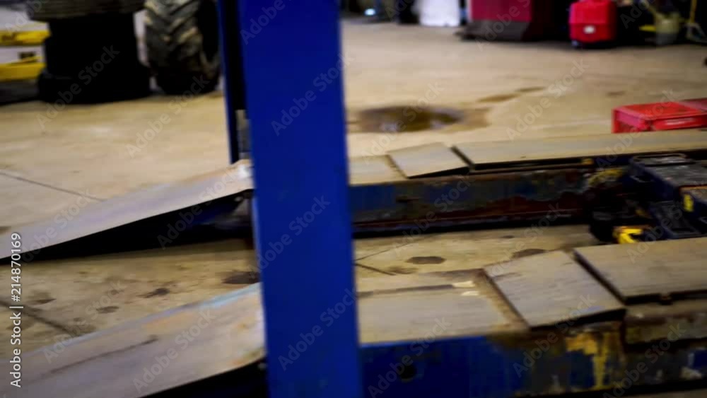 Static shot of a hydraulic car lift in a mechanic auto shop Static shot of a hydraulic car lift in a mechanic auto shop