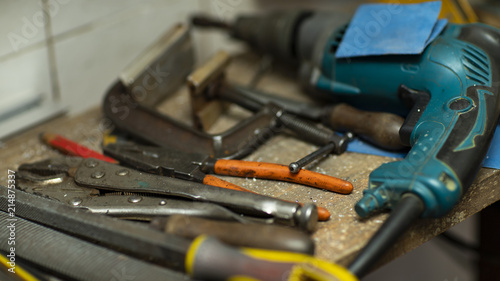 Different types of tools and hand drill on desktop, blurred background 