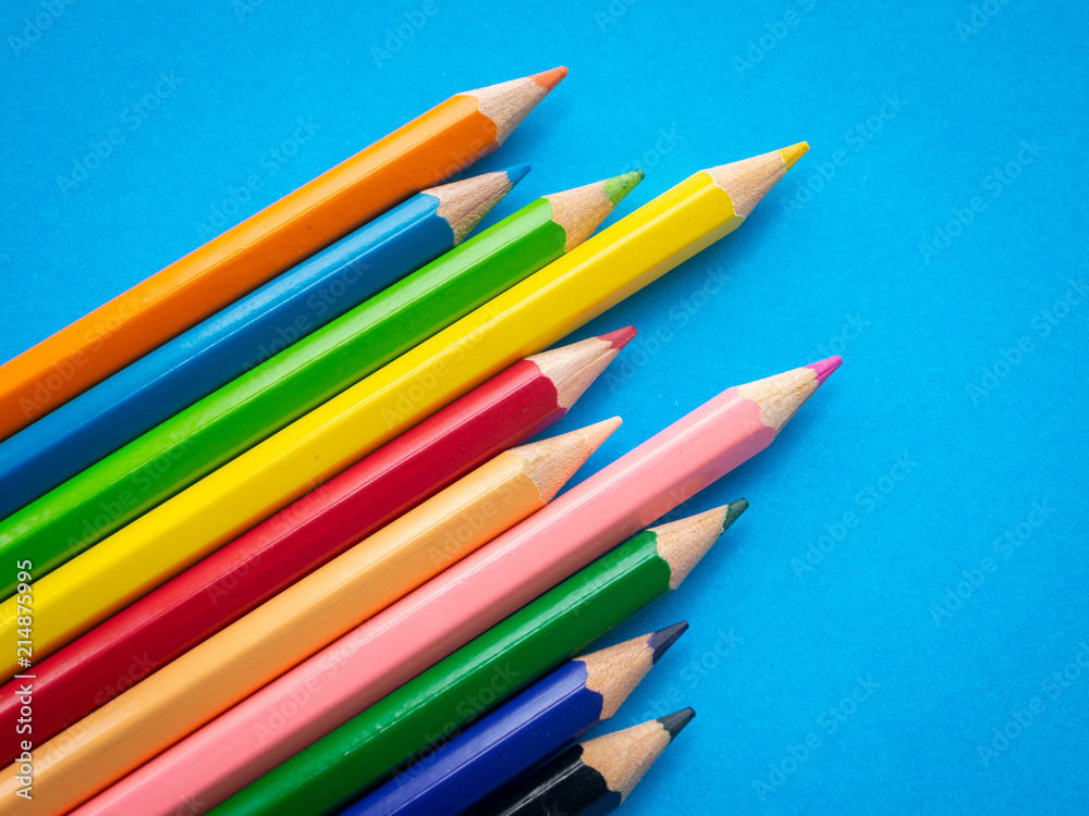 Fototapeta premium Closeup color pencils isolated on blue paper background. Education, Back to school Concept.