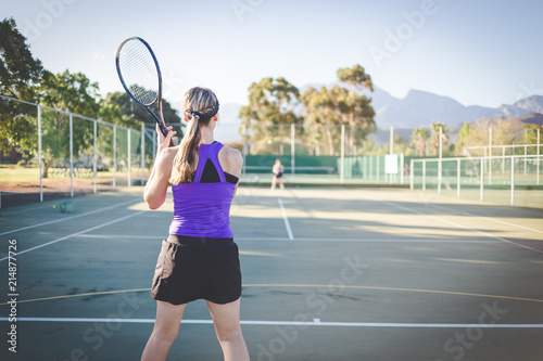 Close up image of a female tennis player playing tennis on a court in bright sunlight © Dewald