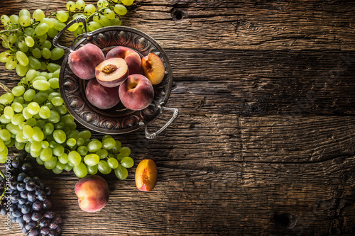 Ripe grapes and peaches in rustic bowl and wooden table