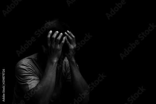 Fototapeta Man sitting alone felling sad worry or fear and hands up on head on black backgr