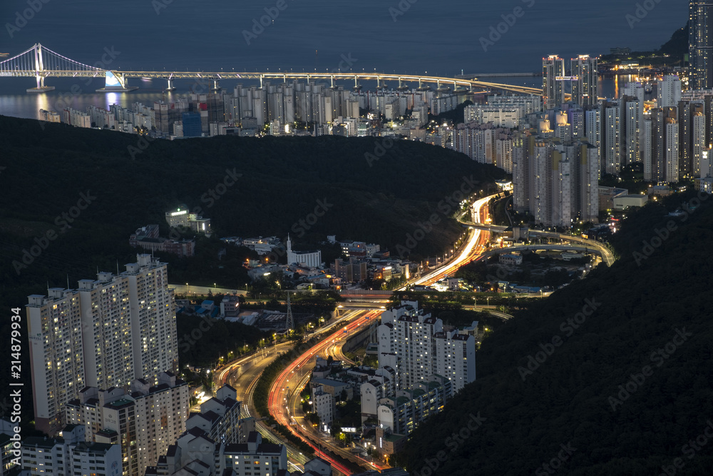 Fototapeta premium Light trains, mountains, city, bridge and sea