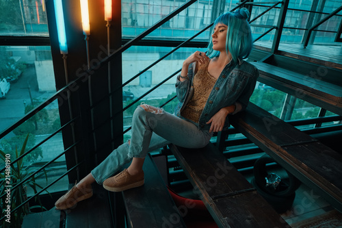  Stylish woman wearing a blue wig sitting on stairs in a modern  photo