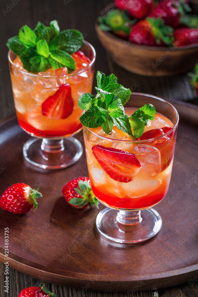 Red cocktail with ice, mint leaves and strawberry on wooden background. Red cocktail with ice, mint leaves and strawberry on wooden background.