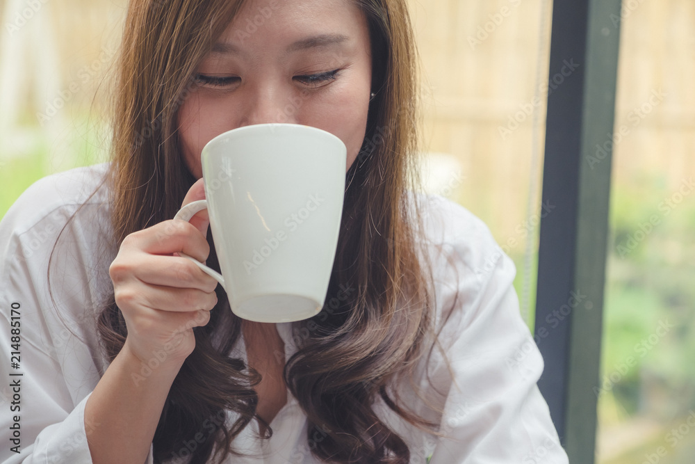 Closeup image of a beautiful asian woman holding and drinking hot coffee with feeling good in cafe Closeup image of a beautiful asian woman holding and drinking hot coffee with feeling good in cafe