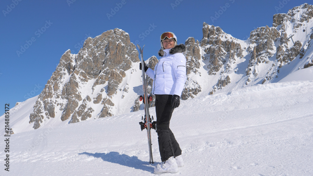 Woman Skier Stands On The Side Of A Mountain Holding Skis