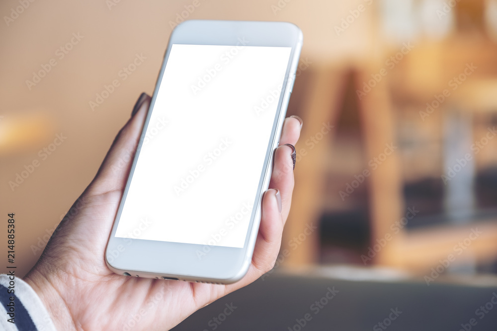 Mockup image of hand holding mobile phone with blank white screen in wooden cafe Mockup image of hand holding mobile phone with blank white screen in wooden cafe