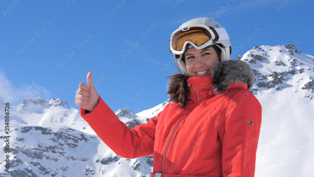 Young Pretty Woman Smiles and Gives a Thumbs Up a Snowy Mountain Background