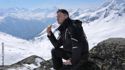 Man Skier Eating A Sandwich Lunch In The Mountains Ski Resort