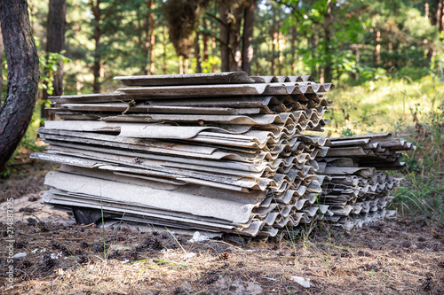 environment pollution - stack of old asbestos slate roof sheets in forest