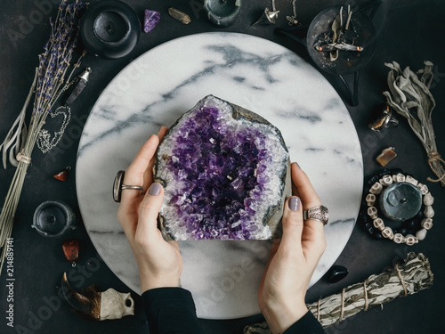 The witch is holding amethyst stone surrounded magic things. View from above. photo