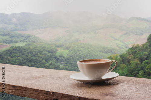 A cup of coffee on the table and a beautiful mountain background.