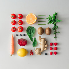 Creative neatly arranged food layout with fruits, vegetables and leaves on bright background. Minimal healthy food concept. Flat lay.
