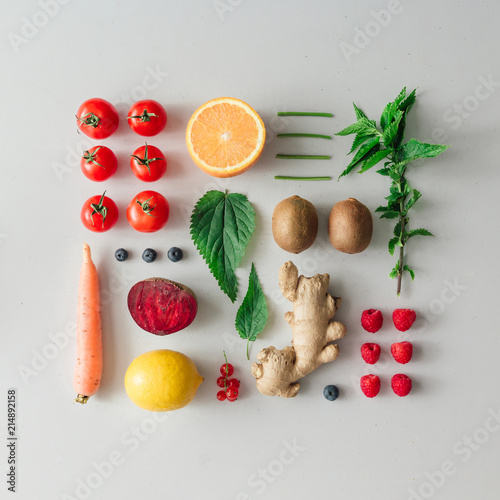 Creative neatly arranged food layout with fruits, vegetables and leaves on bright background. Minimal healthy food concept. Flat lay.