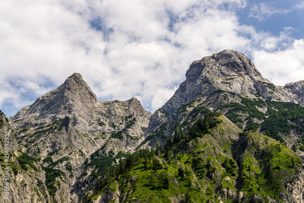Bergmassiv vor Wolkenhimmel hinter Bäumen Bergmassiv vor Wolkenhimmel hinter Bäumen