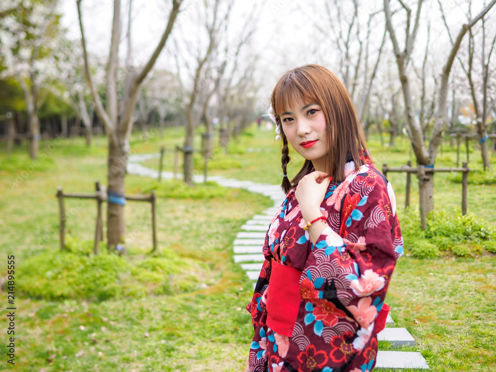 Attractive asian woman wearing kimono in cherry blossom forest in spring.