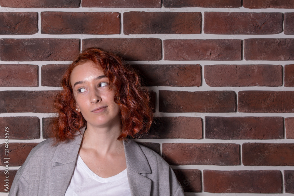 Portrait of a red-haired girl on a brick wall background