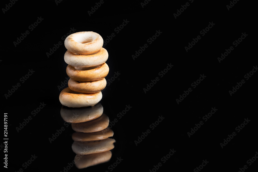 A tower of bagels on a black background with reflection. A tower of bagels on a black background with reflection.