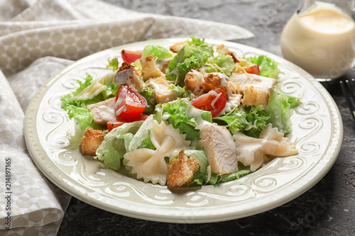 Tasty Caesar salad with pasta on table