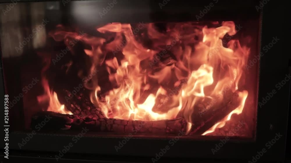 A close up shot of fire burning within an enclosed metal fireplace. A close up shot of fire burning within an enclosed metal fireplace.