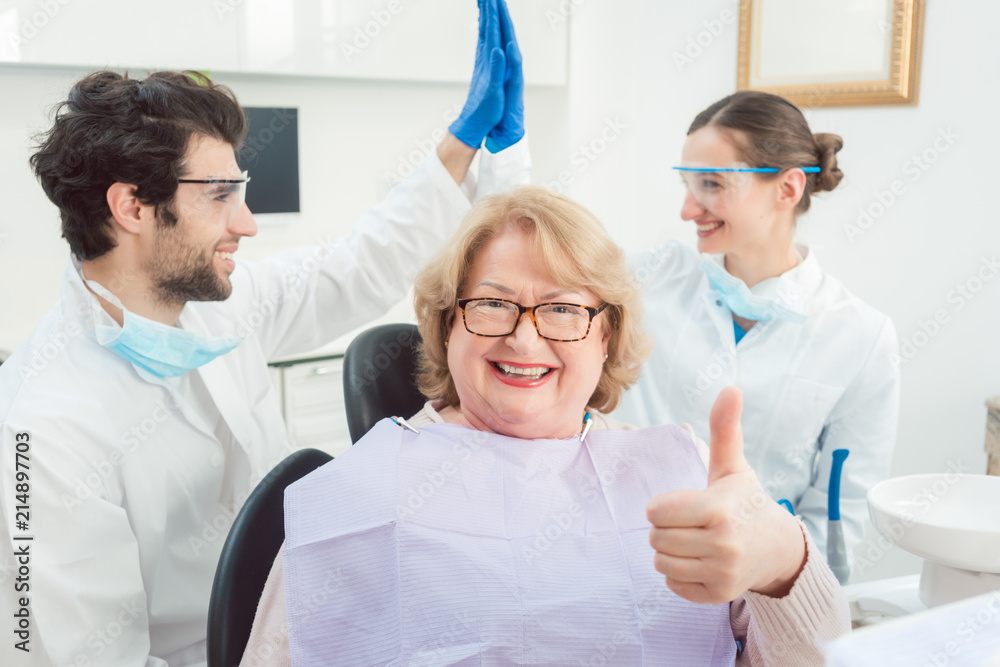 Dentists and patient in surgery being excited showing thumbs up Dentists and patient in surgery being excited showing thumbs up
