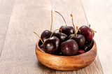 fresh cherry in wood bowl on wooden background 
