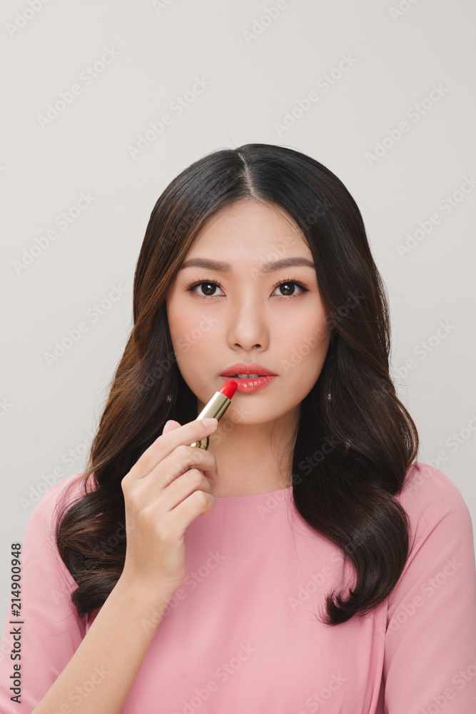 Young happy smiling woman applying lipstick, isolated over white background Young happy smiling woman applying lipstick, isolated over white background