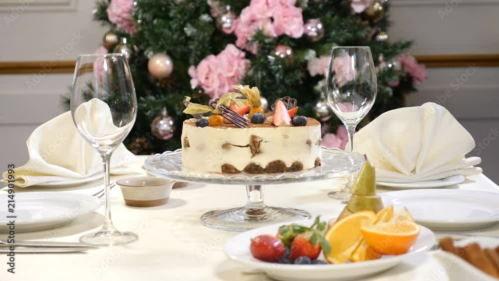 Restaurant concept. New Year and Merry Christmas feast table. Waiter in gloves opens and then closes glass dish with a fruit cake Restaurant concept. New Year and Merry Christmas feast table. Waiter in gloves opens and then closes glass dish with a fruit cake