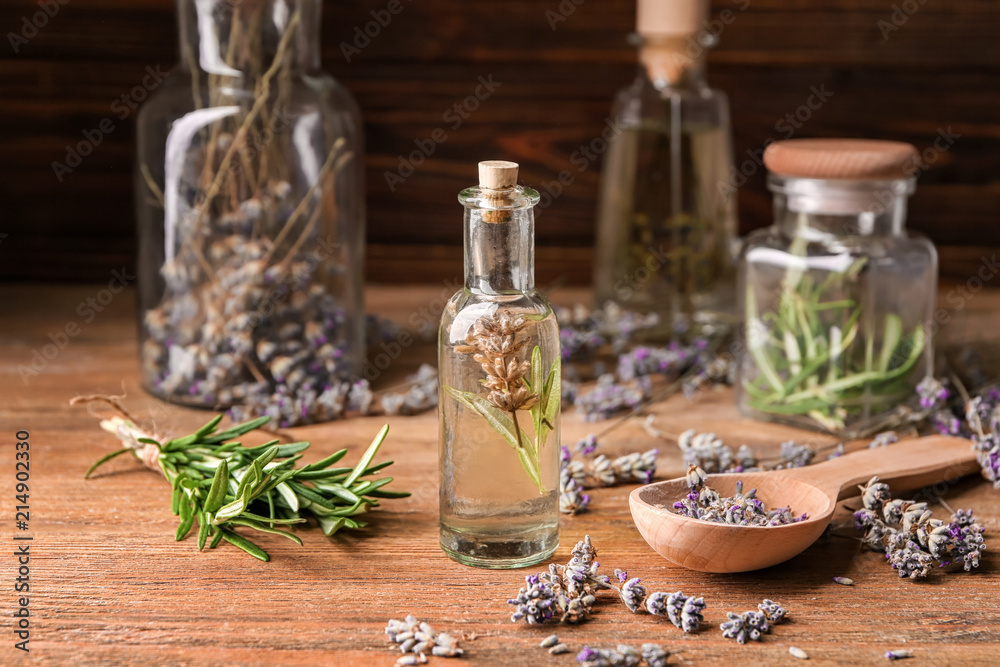 Bottle of essential oil with lavender and rosemary on wooden table Bottle of essential oil with lavender and rosemary on wooden table