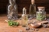 Bottle of essential oil with lavender and rosemary on wooden table