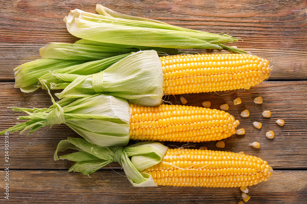 Fresh corncobs on wooden table Fresh corncobs on wooden table