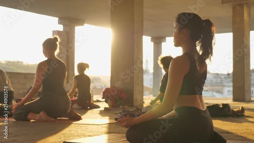 Yogi girl is meditating in group in abandoned building in summer on sunrise, healthy lifestyle, relax concept, sport concept