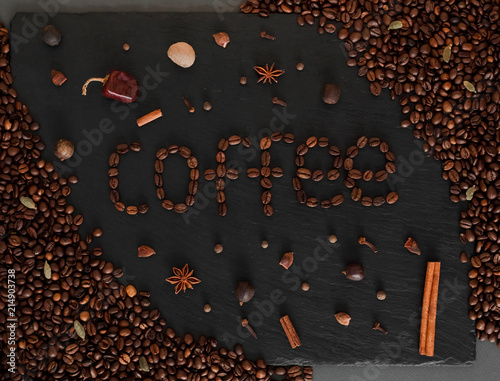 Dark background with coffeeped phrase Coffe. Black texturised background with coffee beans and spices. photo