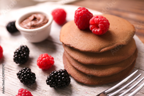 Tasty chocolate pancakes on wooden stand, closeup