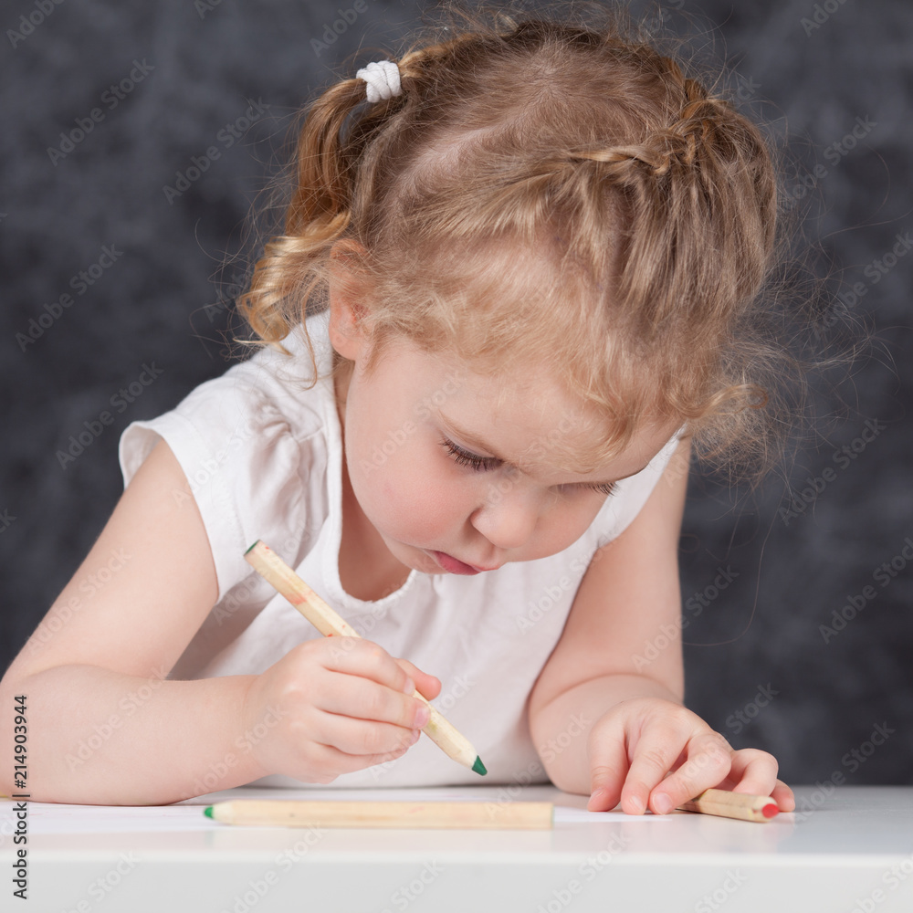 Little girl draws with pencils, portrait on background of school board Little girl draws with pencils, portrait on background of school board