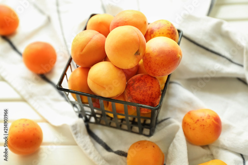 Container with fresh apricots on wooden table
