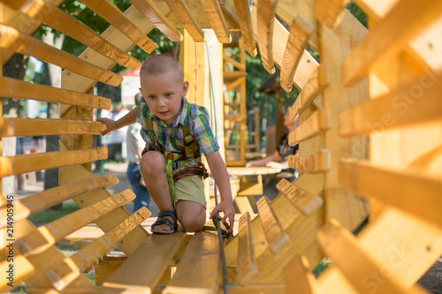 A little boy is climbing on an obstacle course.