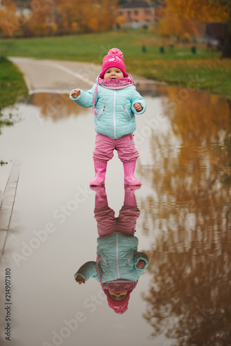 little girl with rubber boots in puddle