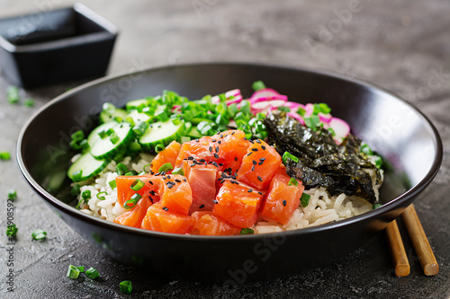 Hawaiian salmon fish poke bowl with rice, radish,cucumber, tomato, sesame seeds and seaweeds. Buddha bowl. Diet food