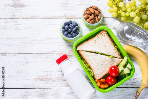 Lunch box with sandwich, vegetables, yogurt, nuts and berries.
