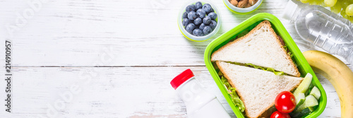 Lunch box with sandwich, vegetables, yogurt, nuts and berries.