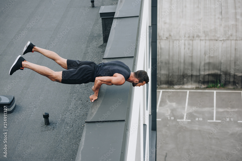 high angle view of sportsman training and standing on hands on roof high angle view of sportsman training and standing on hands on roof
