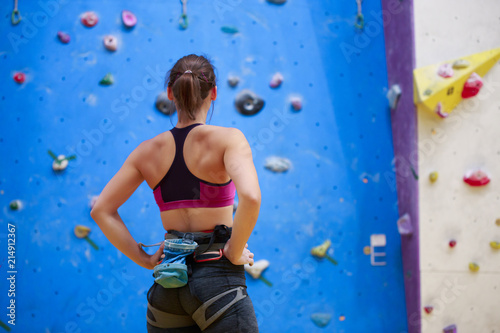 Photo of young athlete from back with hands on waist-standing next to wall for rock climbing
