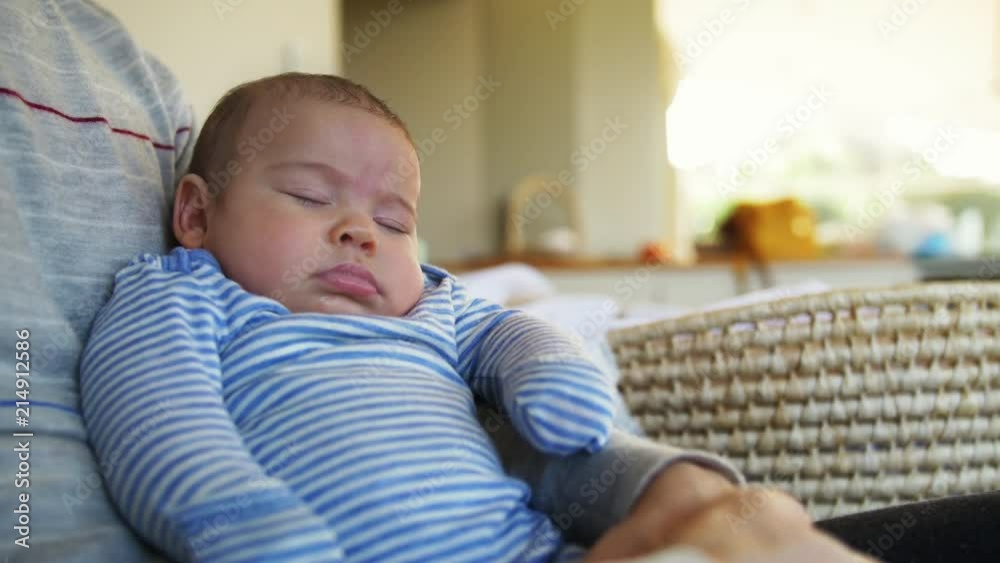 Small baby rocking asleep on lap of father in warm afternoon light Small baby rocking asleep on lap of father in warm afternoon light