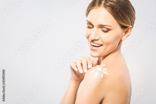 Young beautiful woman with sun-shaped sun cream. Pretty woman ready for suntan treatment. Sunscreen lotion sun drawing on woman shoulder. Isolated on white background.