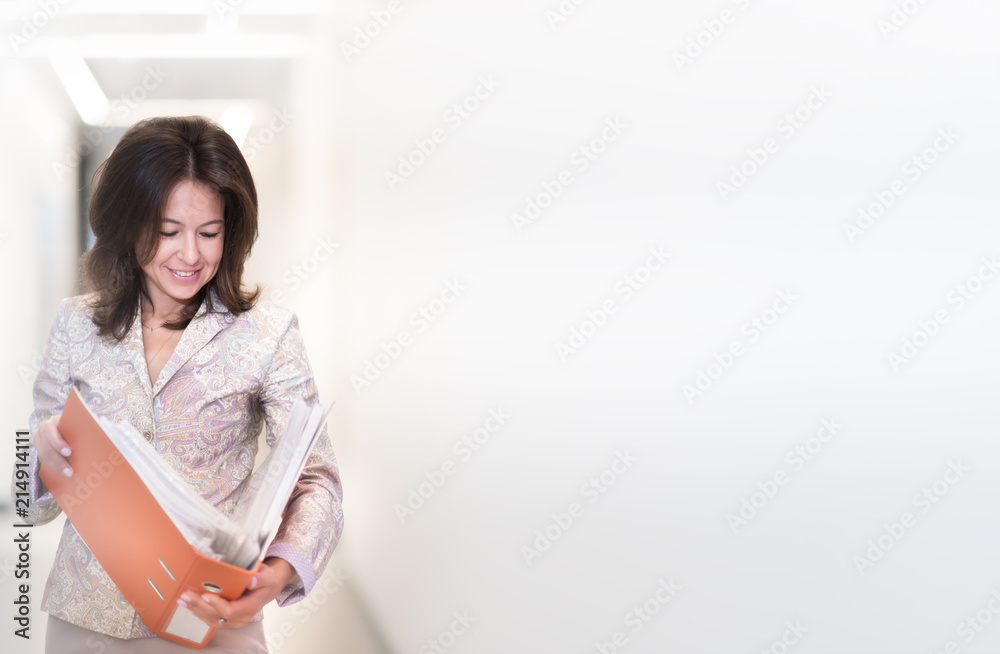 Portrait of confident beautiful middle age business woman holding orange folder in her hands standing on light background. Copyspace Portrait of confident beautiful middle age business woman holding orange folder in her hands standing on light background. Copyspace