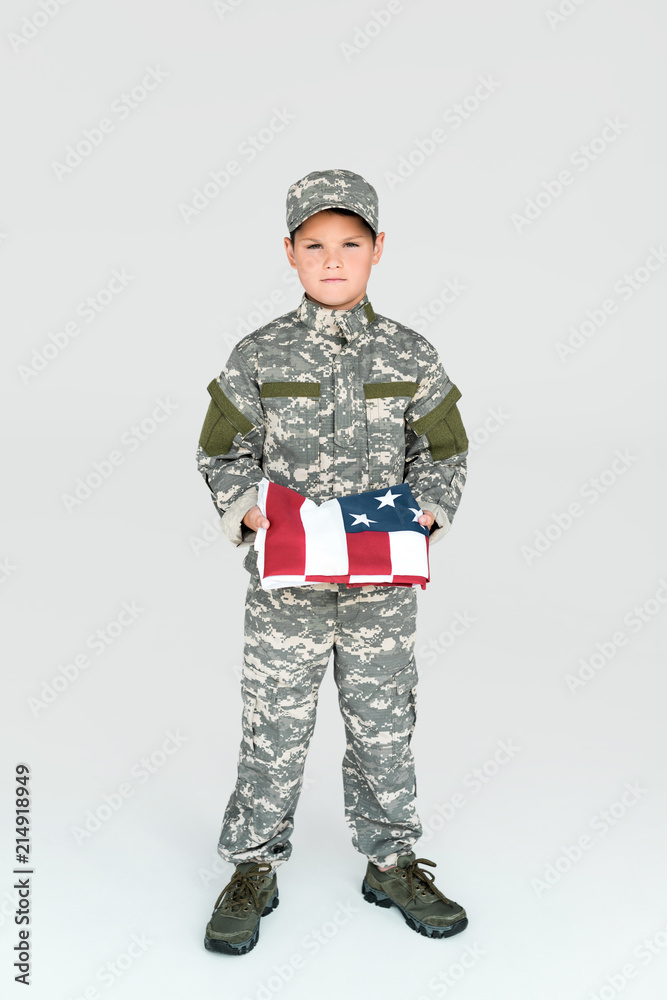 boy in military uniform holding folded american flag in hands on grey background boy in military uniform holding folded american flag in hands on grey background
