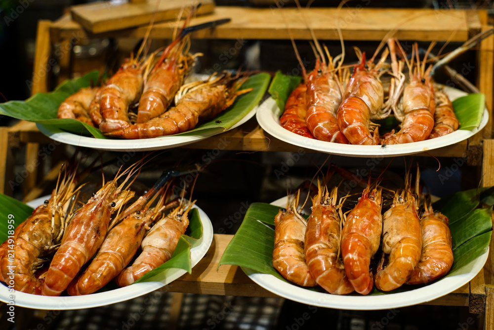 Grilled River Prawn wrapped in Banana leaf and placed on a white plate.
