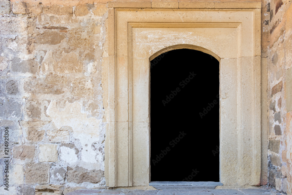 A door in a stone wall is isolated on a black background with copy space